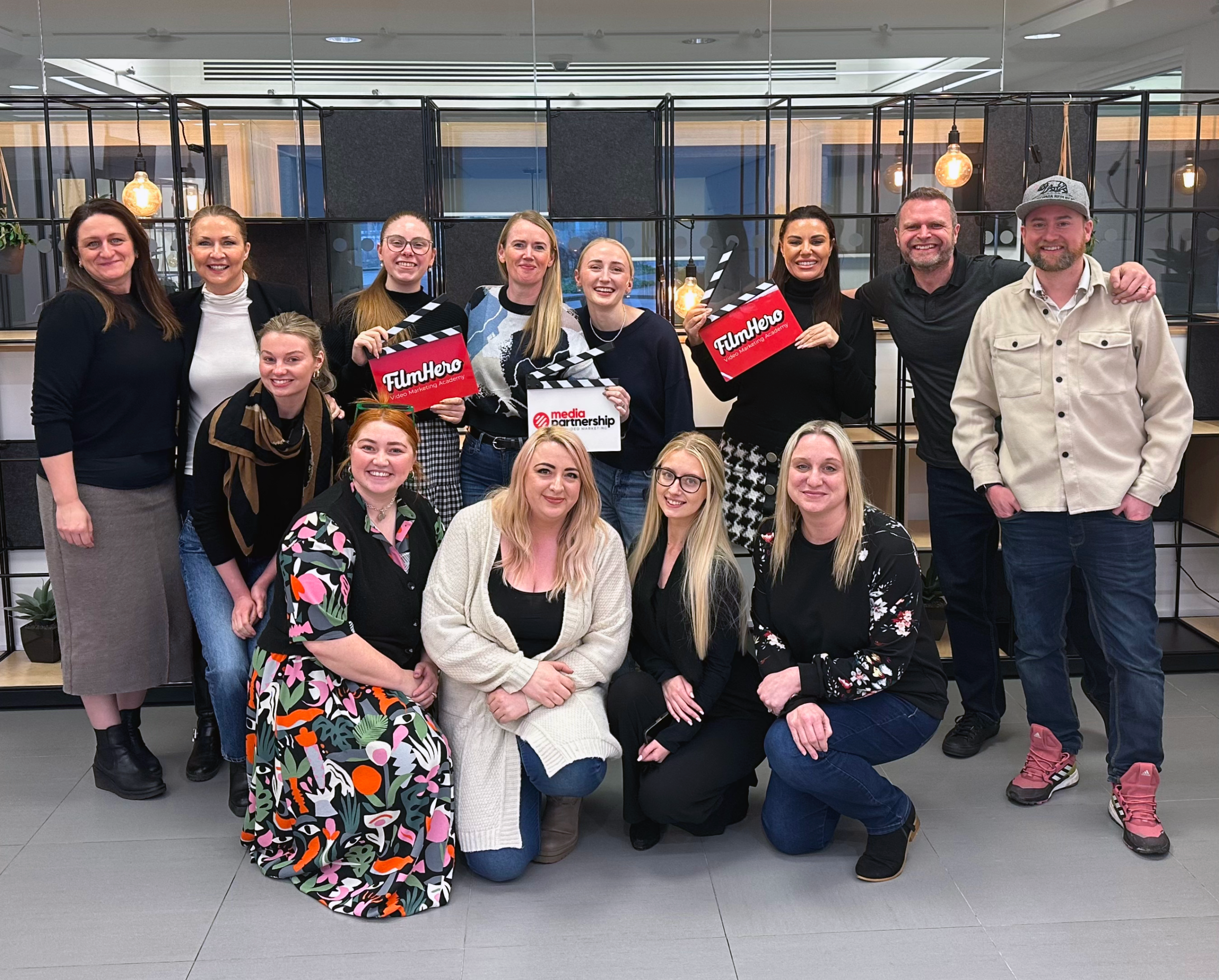 The team from a FilmHero strategy day with Mark, holding FilmHero and Media Partnership clapperboards